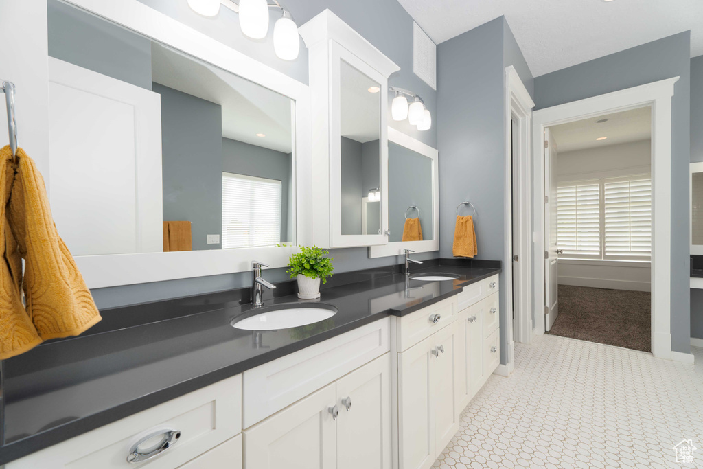 Bathroom featuring a healthy amount of sunlight, tile patterned floors, and dual vanity