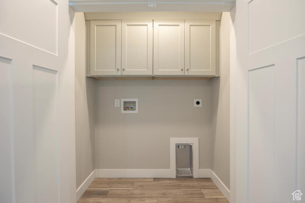 Laundry area featuring cabinets, light hardwood / wood-style flooring, hookup for an electric dryer, and washer hookup