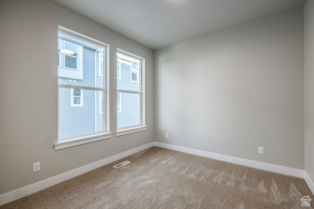 Unfurnished room featuring plenty of natural light and carpet floors