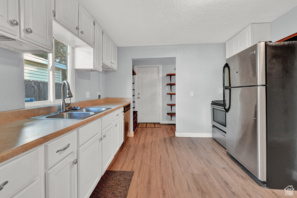 Kitchen featuring white cabinetry, sink, light hardwood / wood-style flooring, and stainless steel appliances