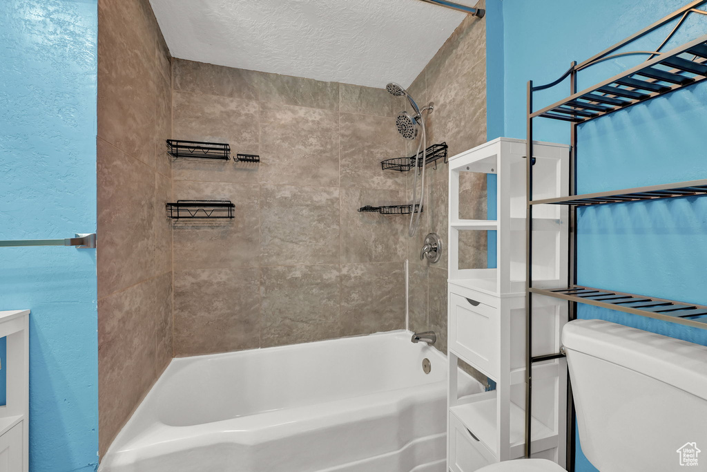 Full bathroom featuring a textured ceiling, vanity, toilet, and tiled shower / bath