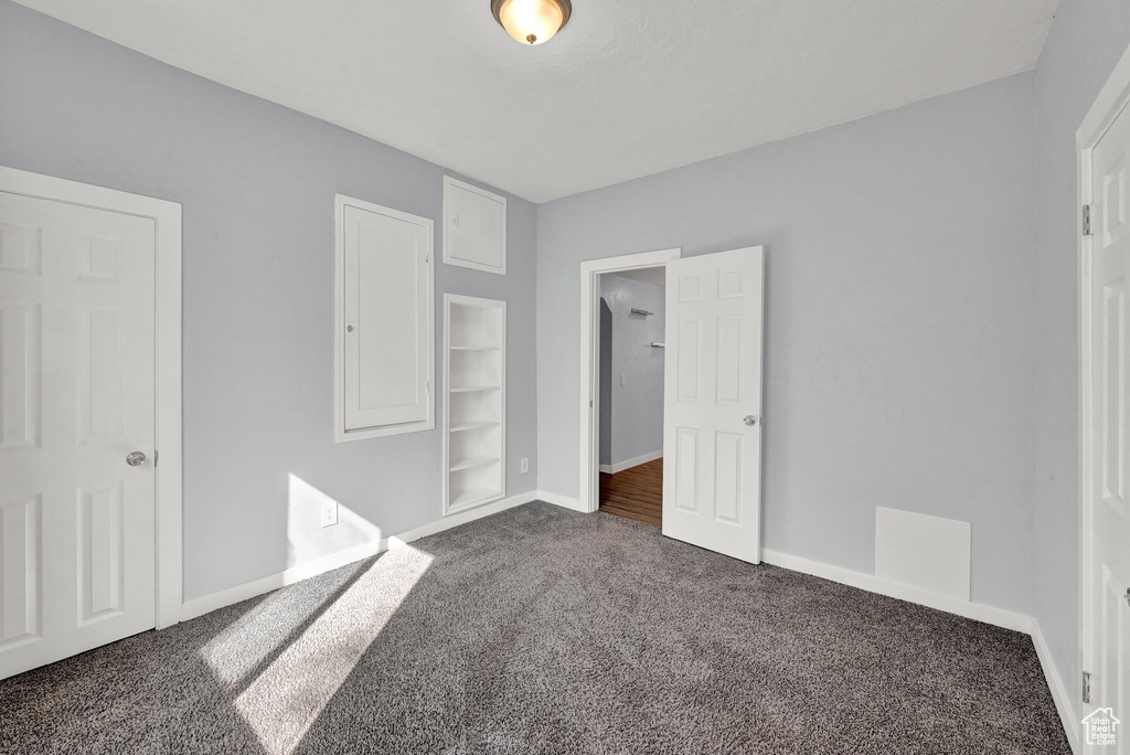 Unfurnished bedroom featuring dark colored carpet