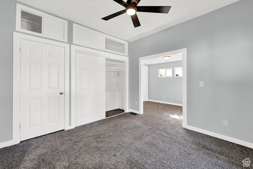 Unfurnished bedroom with dark carpet, a closet, and ceiling fan