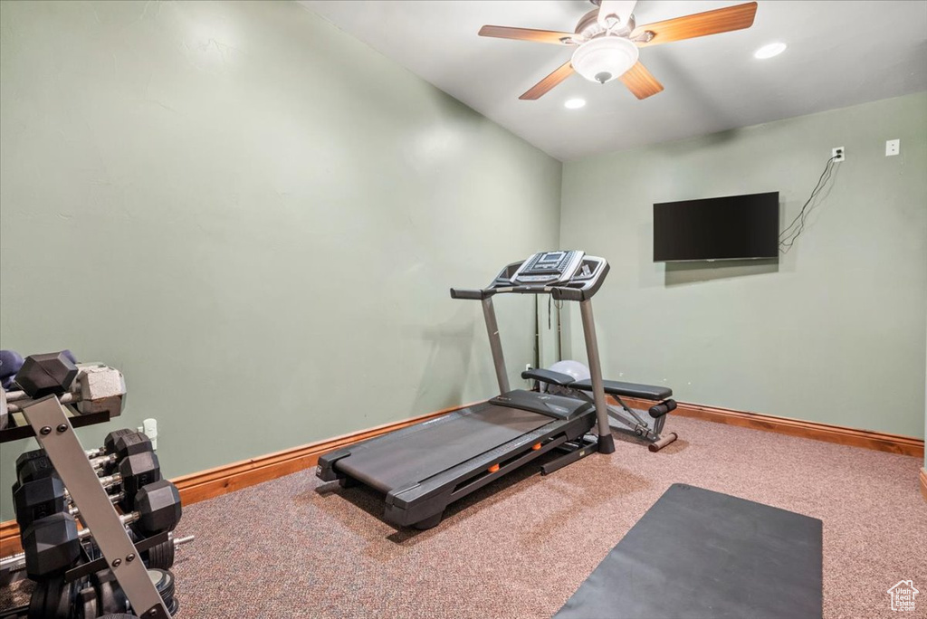 Exercise room featuring ceiling fan, vaulted ceiling, and carpet