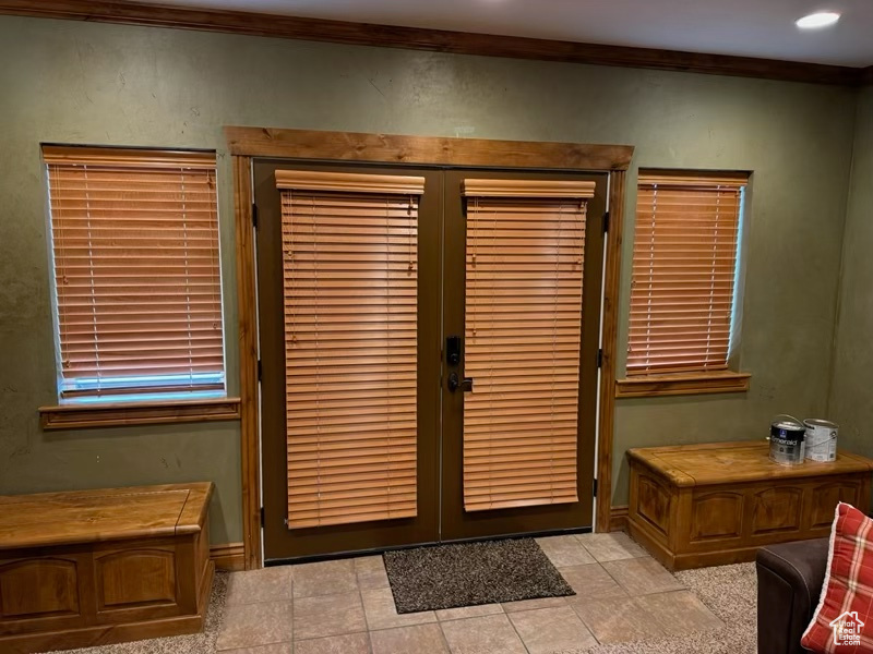 Doorway to outside with light tile patterned floors, crown molding, and french doors