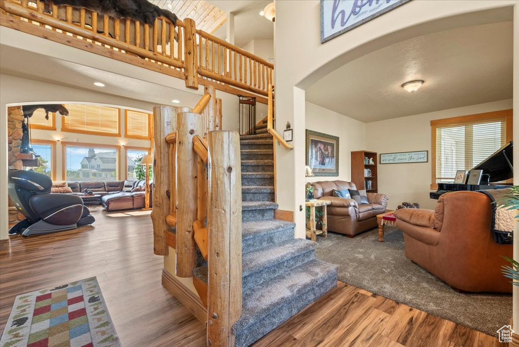 Stairs featuring wood-type flooring, a high ceiling, and a healthy amount of sunlight