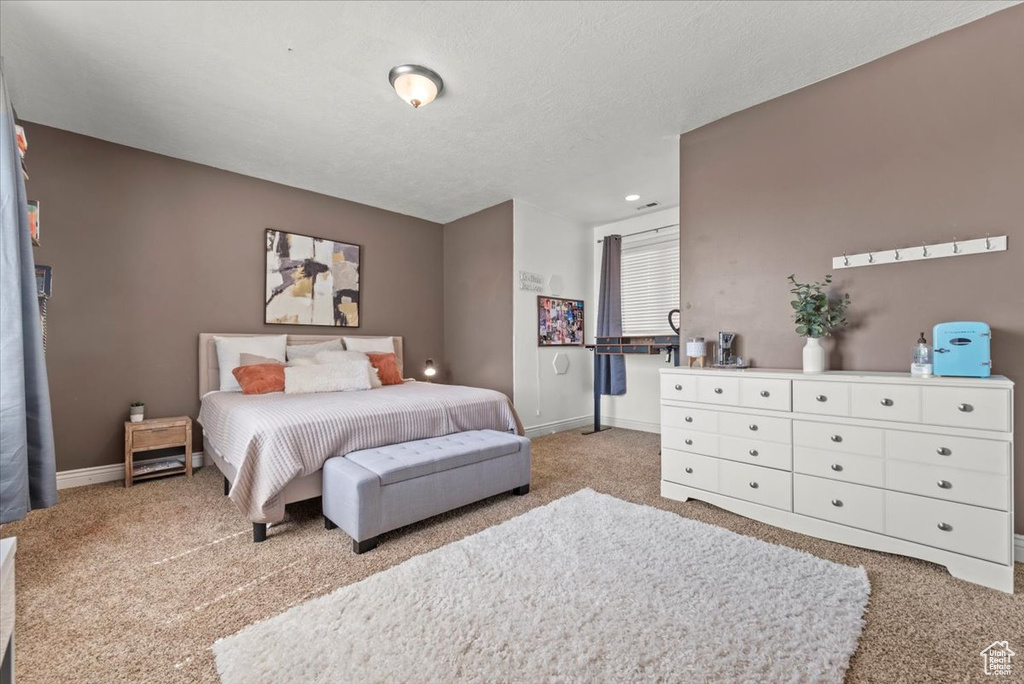 Bedroom with a textured ceiling and light carpet