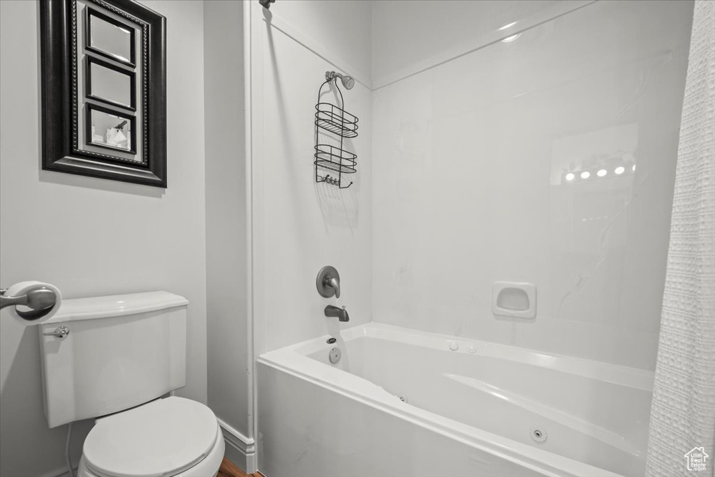 Bathroom featuring shower / bathtub combination with curtain and toilet