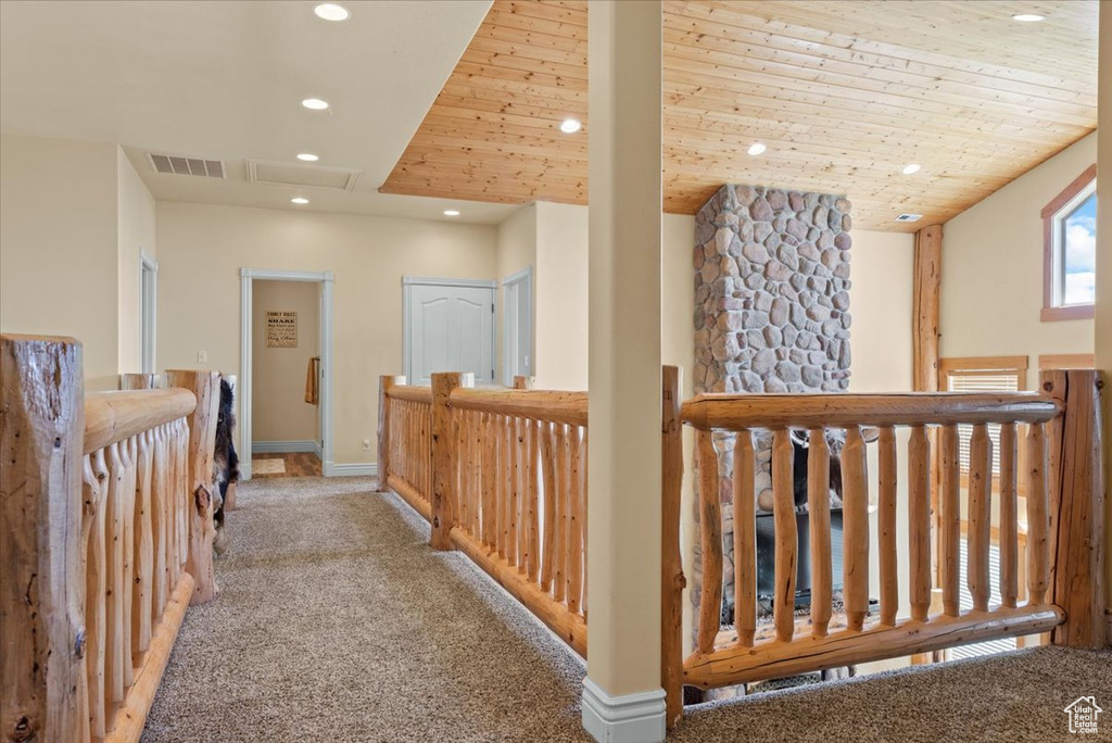 Corridor featuring light colored carpet and wood ceiling