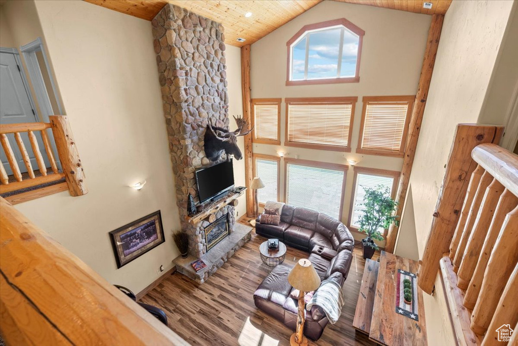 Living room featuring high vaulted ceiling, a stone fireplace, wood ceiling, and hardwood / wood-style flooring