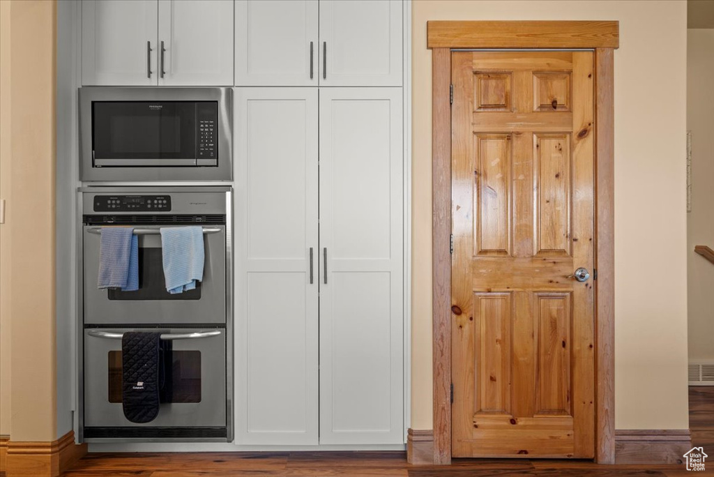 Kitchen featuring white cabinets, stainless steel appliances, and hardwood / wood-style flooring