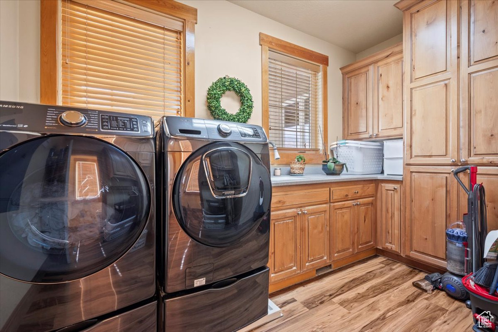 Laundry area featuring light hardwood / wood-style flooring, washing machine and clothes dryer, and cabinets