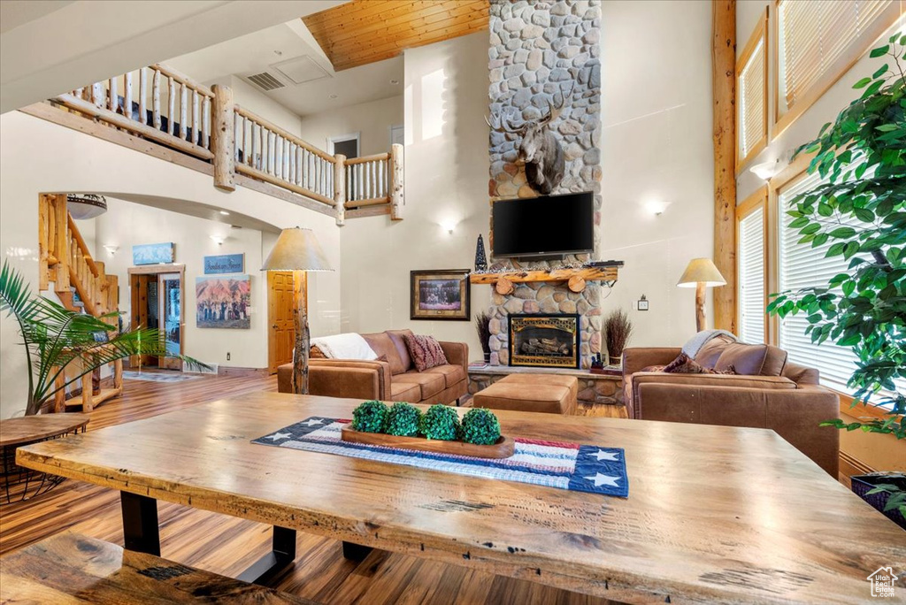 Living room with hardwood / wood-style floors, a towering ceiling, wooden ceiling, and a fireplace