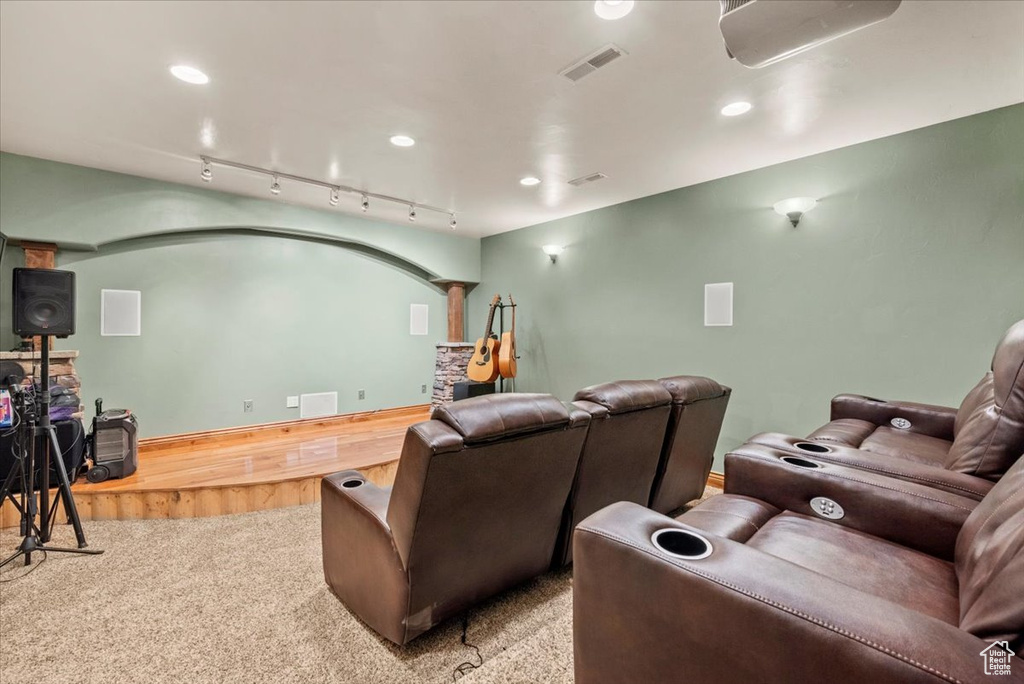 Carpeted home theater room with rail lighting