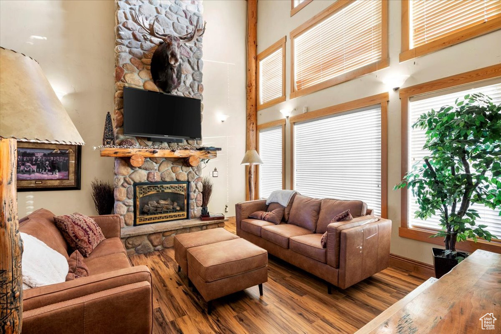 Living room featuring a towering ceiling, hardwood / wood-style flooring, and a stone fireplace