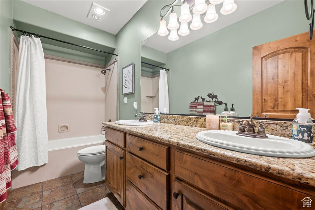 Full bathroom with double vanity, shower / bath combo, toilet, and tile patterned floors