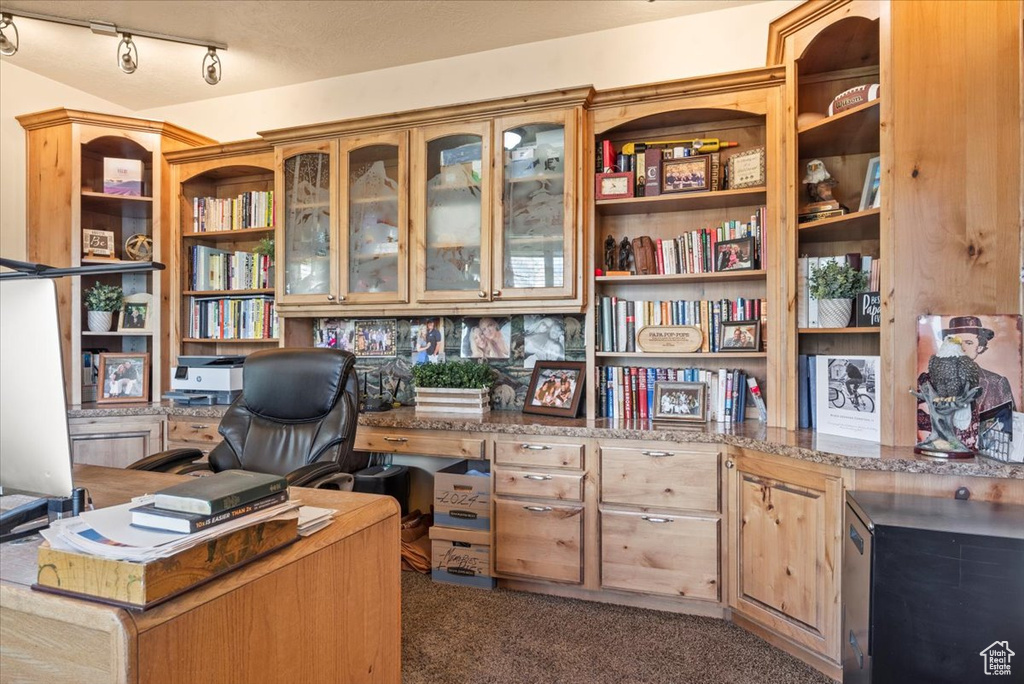 Home office with dark carpet, rail lighting, and built in desk