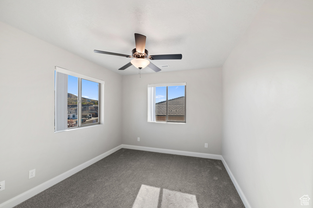 Carpeted empty room featuring ceiling fan and plenty of natural light