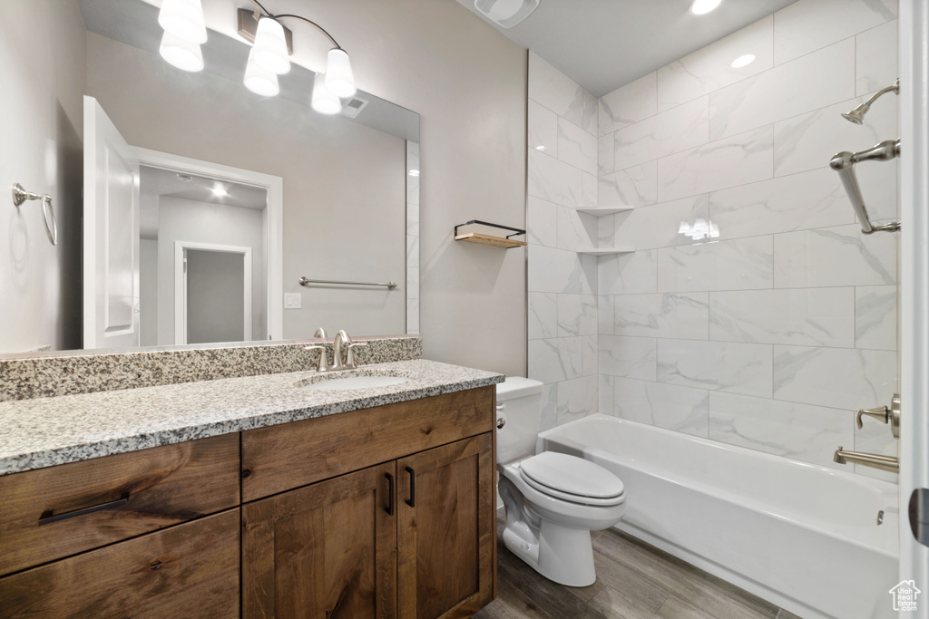 Full bathroom with vanity, tiled shower / bath, wood-type flooring, and toilet