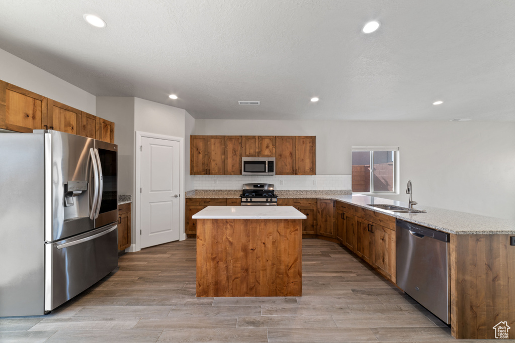 Kitchen featuring stainless steel appliances, light hardwood / wood-style flooring, sink, and a kitchen island