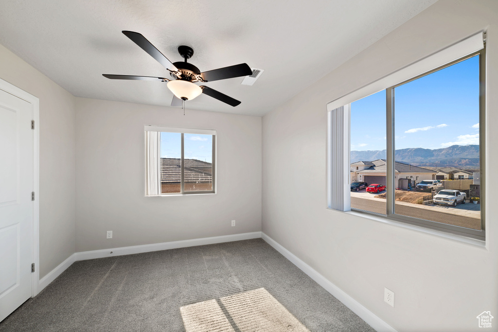 Carpeted spare room featuring a mountain view and ceiling fan