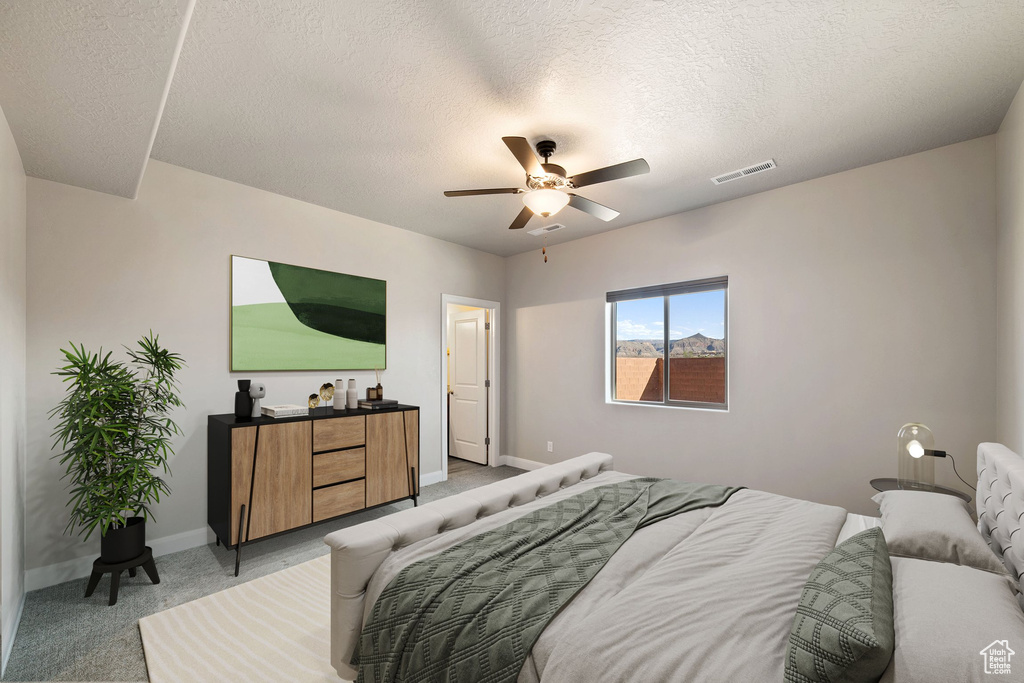 Bedroom with ceiling fan, a textured ceiling, and light carpet