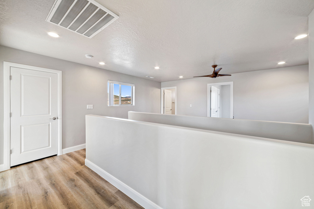 Hallway featuring light wood-type flooring and a textured ceiling