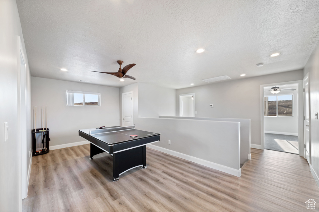 Game room featuring light hardwood / wood-style flooring, a textured ceiling, and ceiling fan