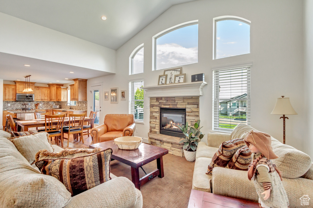 Living room featuring sink, a fireplace, light hardwood / wood-style floors, and high vaulted ceiling