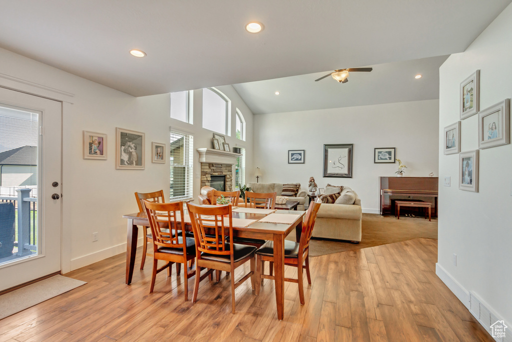 Dining room featuring a fireplace, light hardwood / wood-style flooring, high vaulted ceiling, and ceiling fan