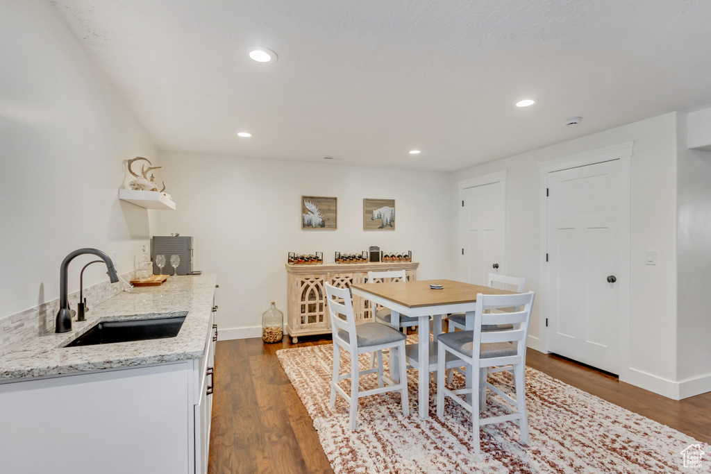 Kitchen with sink, white cabinetry, light stone counters, and dark hardwood / wood-style floors