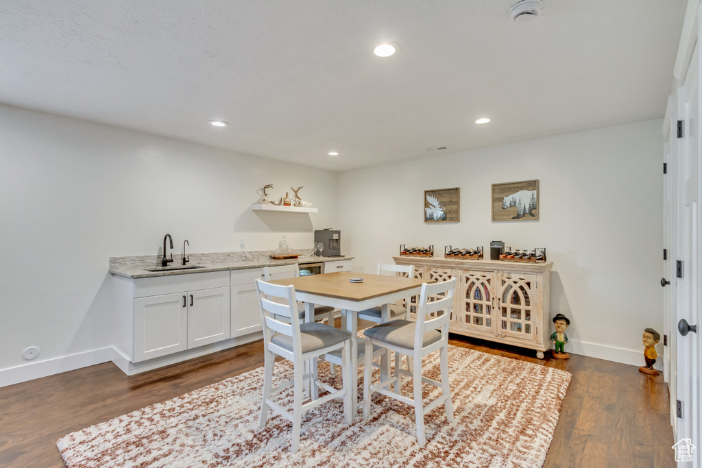 Kitchen featuring sink, dark hardwood / wood-style floors, light stone counters, and white cabinets