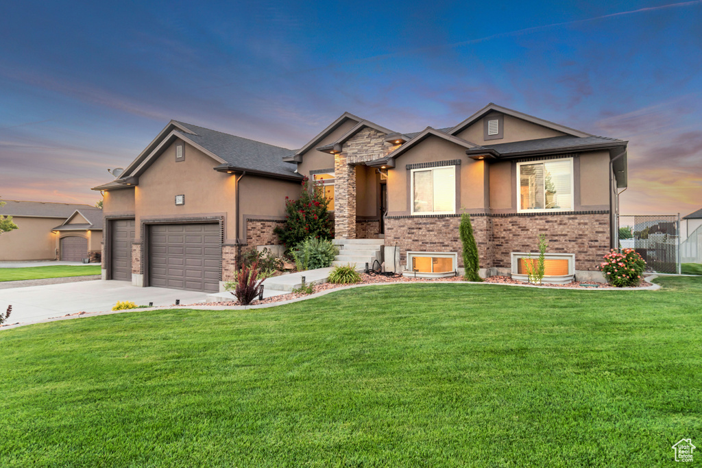 View of front of property with a garage and a lawn