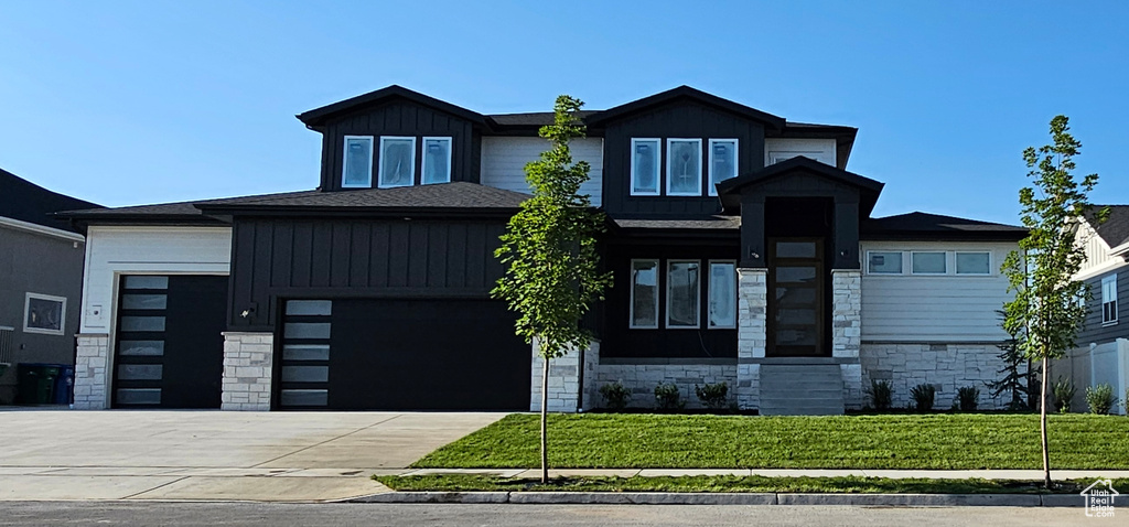 View of front of property with a garage and a front lawn