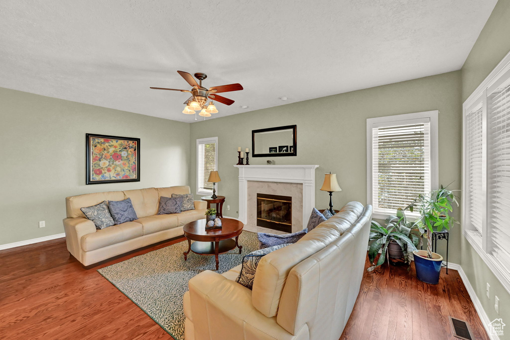 Living room featuring dark hardwood / wood-style floors, a high end fireplace, and ceiling fan