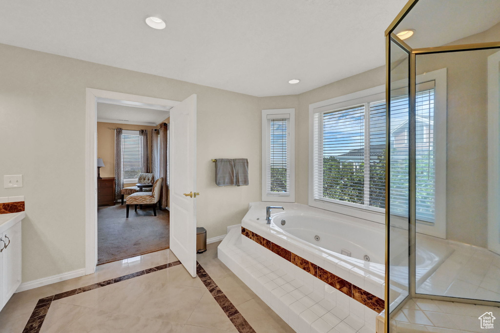 Bathroom featuring a relaxing tiled tub, tile patterned flooring, and vanity