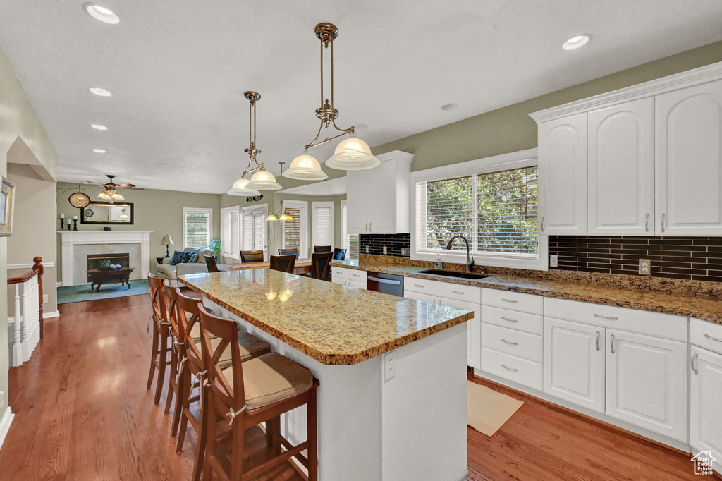 Kitchen with a healthy amount of sunlight, a premium fireplace, white cabinetry, and backsplash