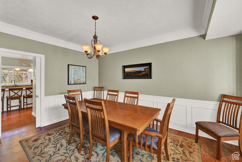 Dining area with a notable chandelier, hardwood / wood-style floors, and ornamental molding