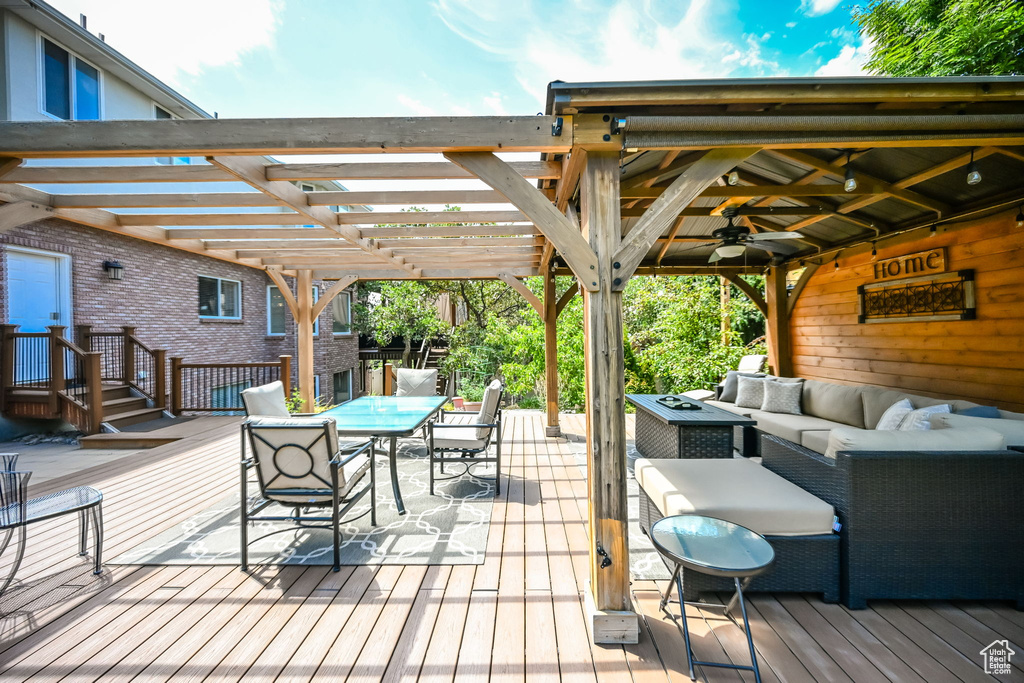 Wooden deck featuring ceiling fan, an outdoor hangout area, and a pergola