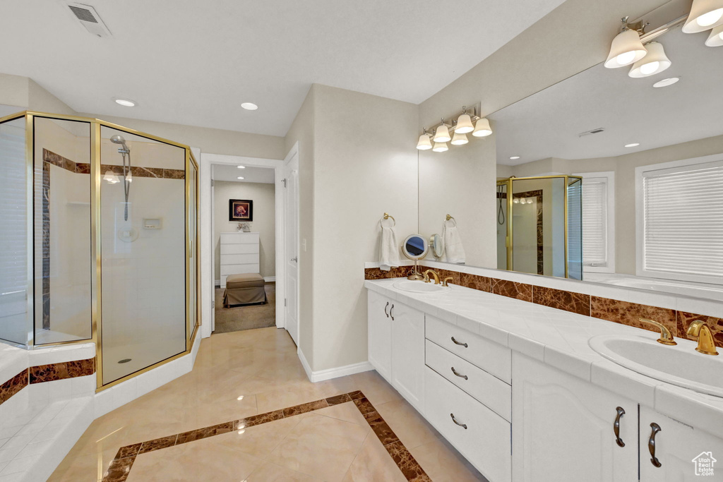 Bathroom with an enclosed shower, tile patterned flooring, and dual bowl vanity