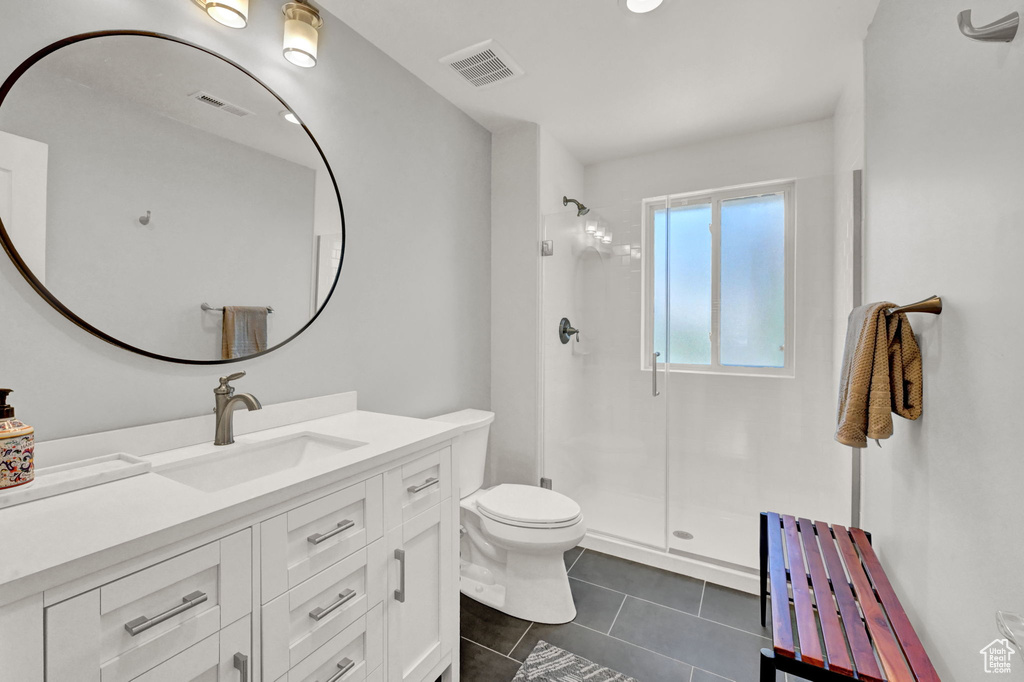 Bathroom with vanity, tile patterned floors, walk in shower, and toilet