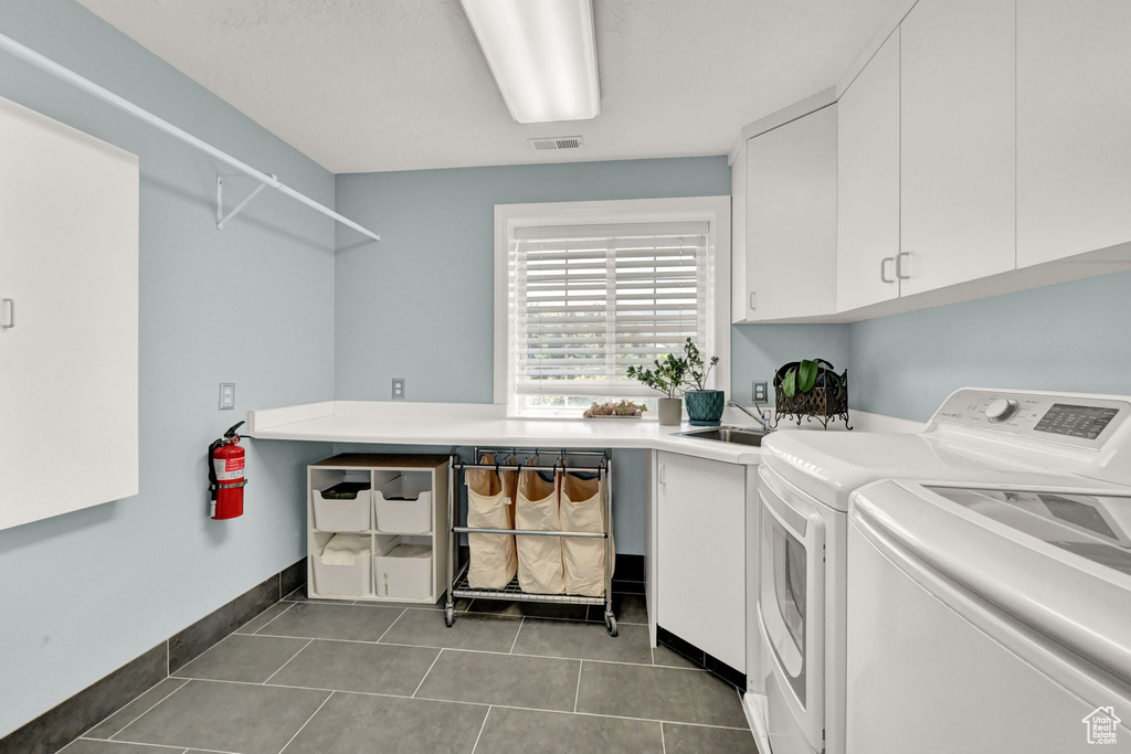 Laundry room featuring separate washer and dryer, tile patterned floors, sink, and cabinets