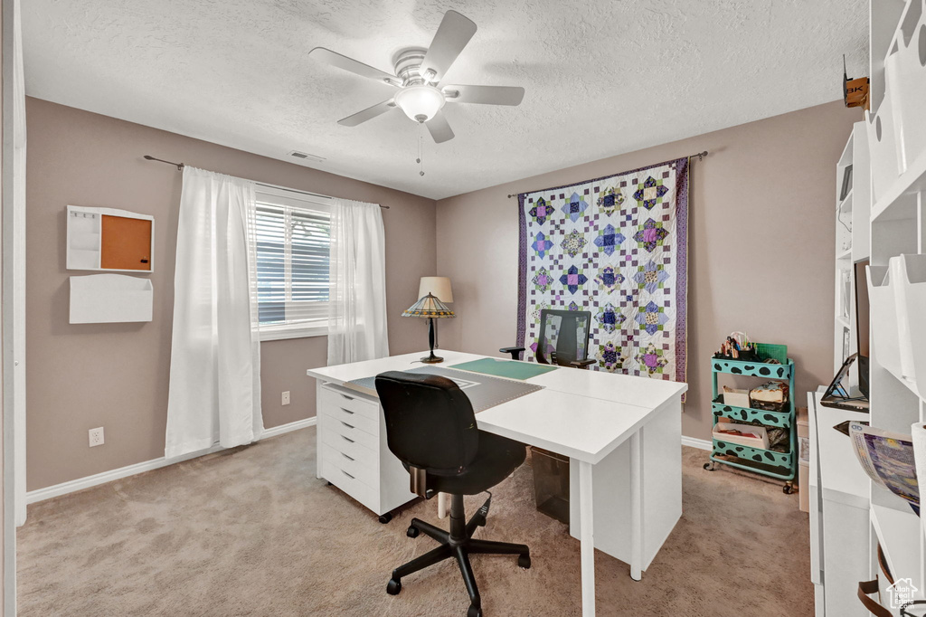 Home office with a textured ceiling, light colored carpet, and ceiling fan