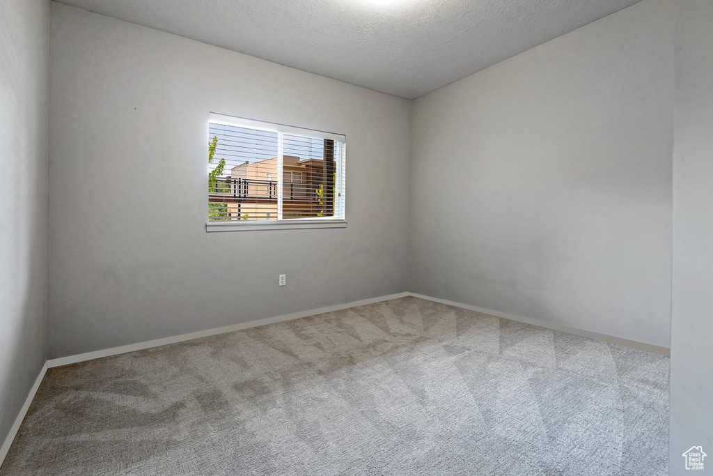 Carpeted empty room featuring a textured ceiling