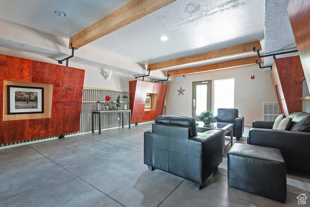 Living room with concrete floors, beamed ceiling, and a textured ceiling