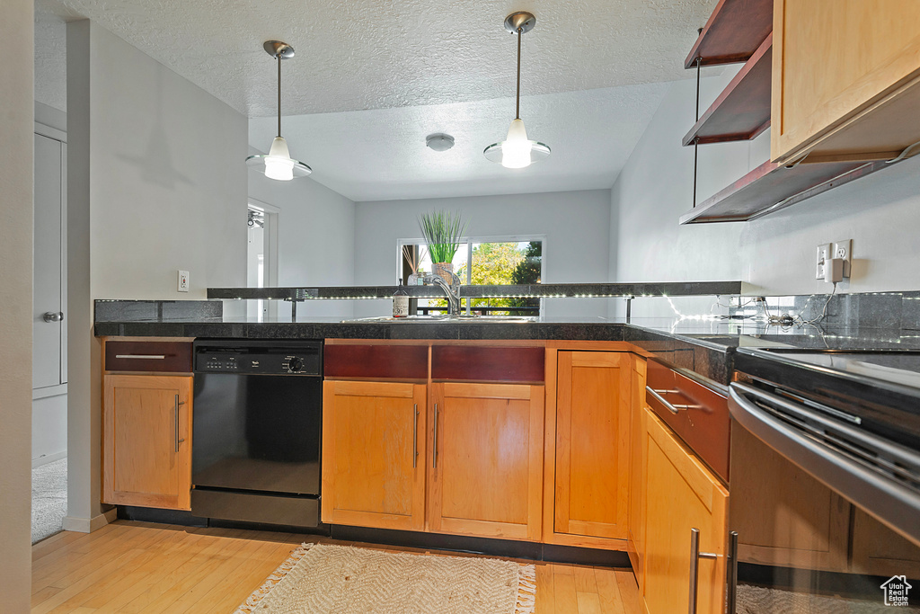 Kitchen with decorative light fixtures, light wood-type flooring, sink, dishwasher, and a textured ceiling