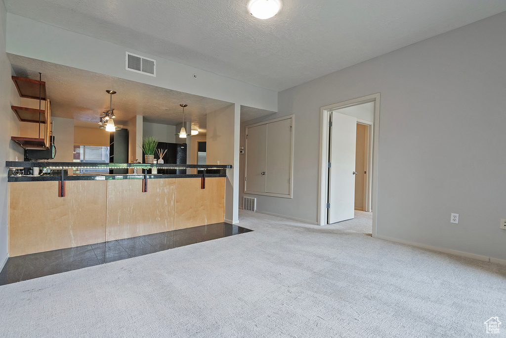 Kitchen featuring ceiling fan, light carpet, decorative light fixtures, and kitchen peninsula