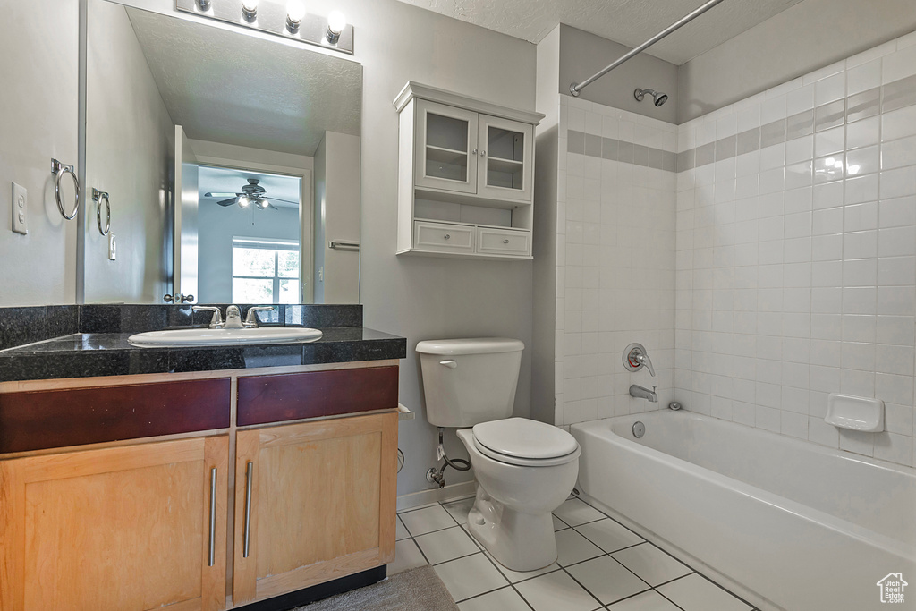 Full bathroom featuring tiled shower / bath combo, tile patterned floors, toilet, vanity, and ceiling fan