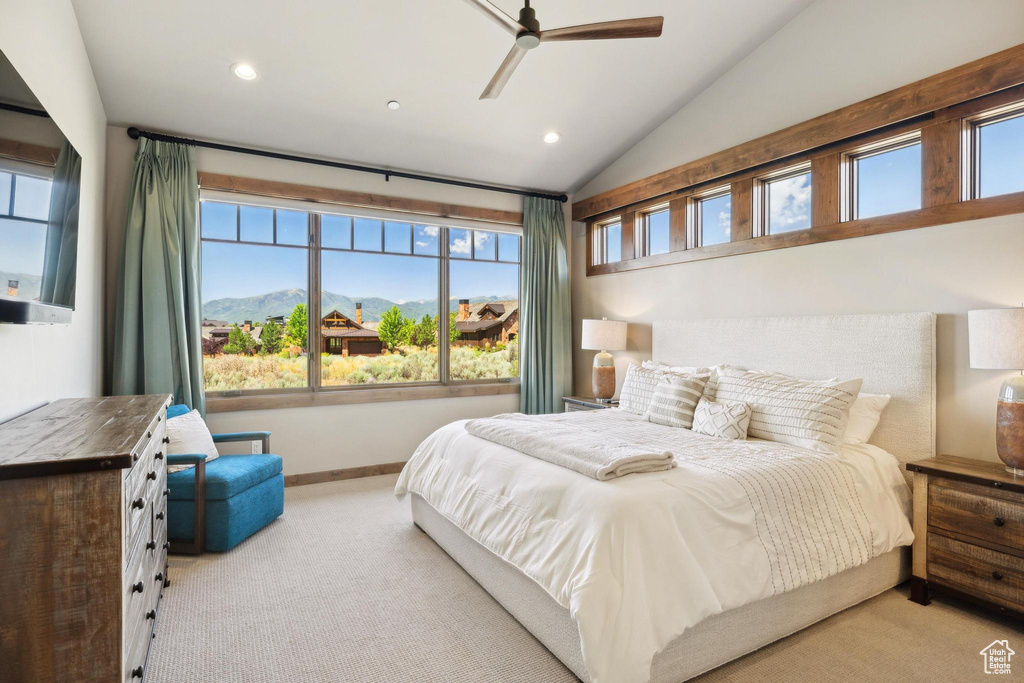 Bedroom with light carpet, vaulted ceiling, ceiling fan, and multiple windows