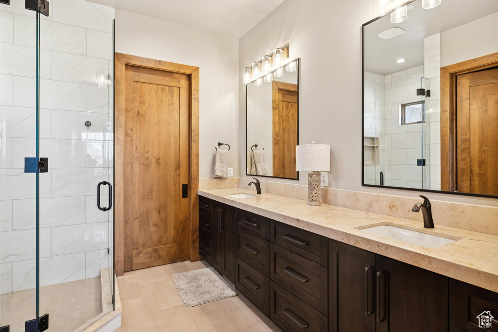 Bathroom with a shower with door, double vanity, and tile patterned flooring